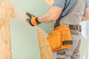 House Remodeling Worker. Caucasian Men with Piece of Drywall in Hands. Building New Wall. Construction Industry Theme.